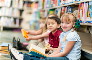 Three children sitting and reading in a library